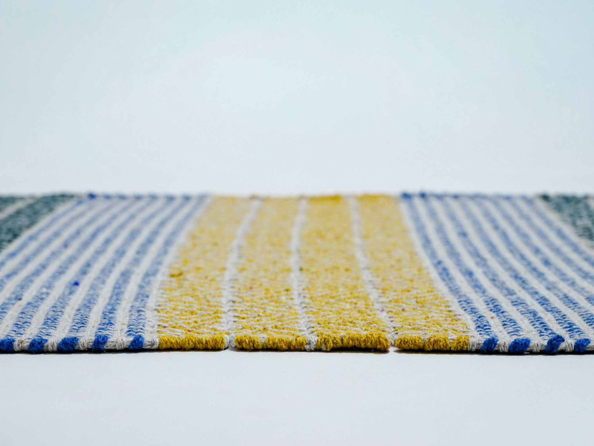 Close-up of hand-braided weave texture on the Meher rag rug in yellow