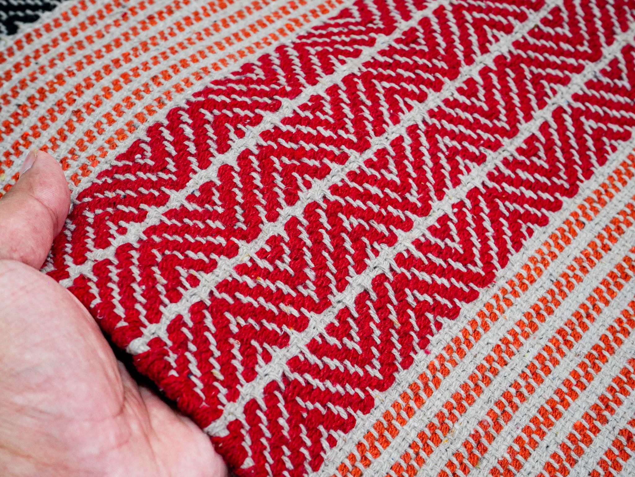 Close-up of hand-braided weave texture on the Meher rag rug in red