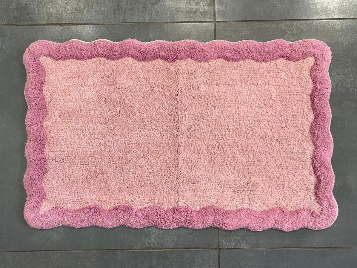 Scallop pattern printed cotton bath mat in pink colourway, studio shot on white background