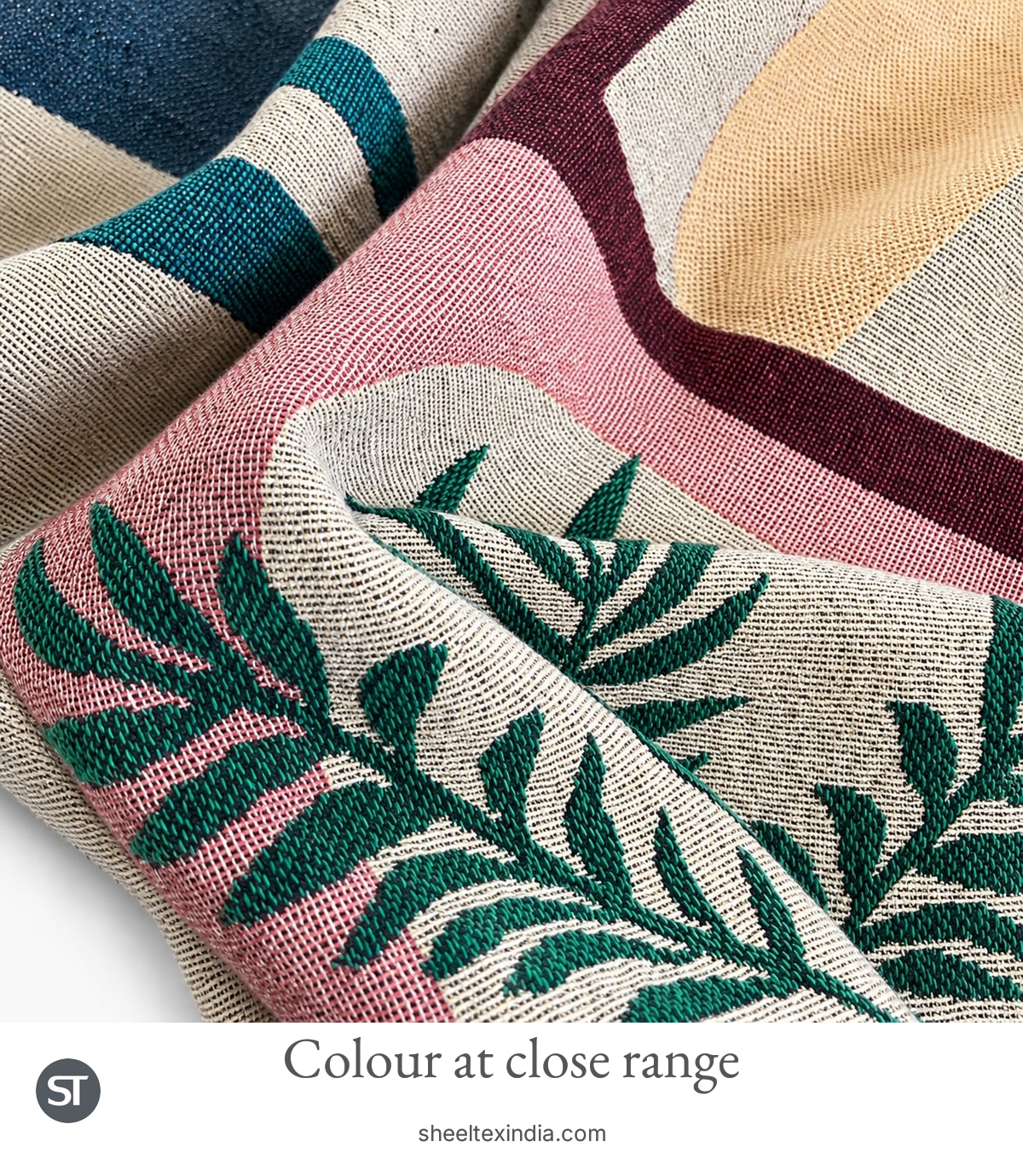 Close view of crossing threads in cream, navy and pink areas beside a green leaf motif on the pictorial throw.