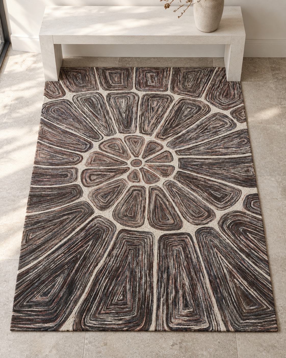 A wool carpet with a small central rosette and dark nested shapes radiating across a light ground, beneath a console.